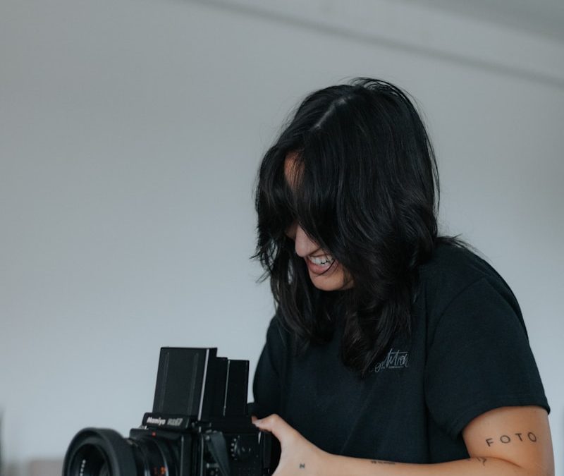woman in black t-shirt holding black dslr camera